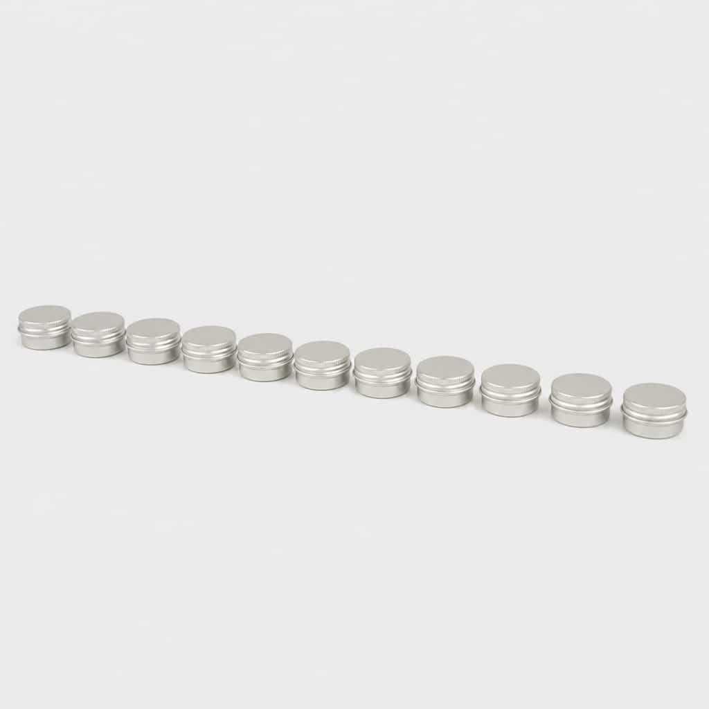 Douze très petits pots en aluminium alignés sur fond clair