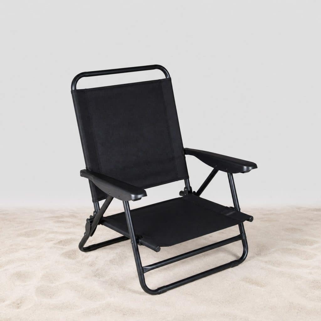 Siège de plage noir plié posé sur le sable